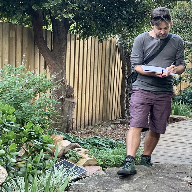 Man walking around the garden taking notes